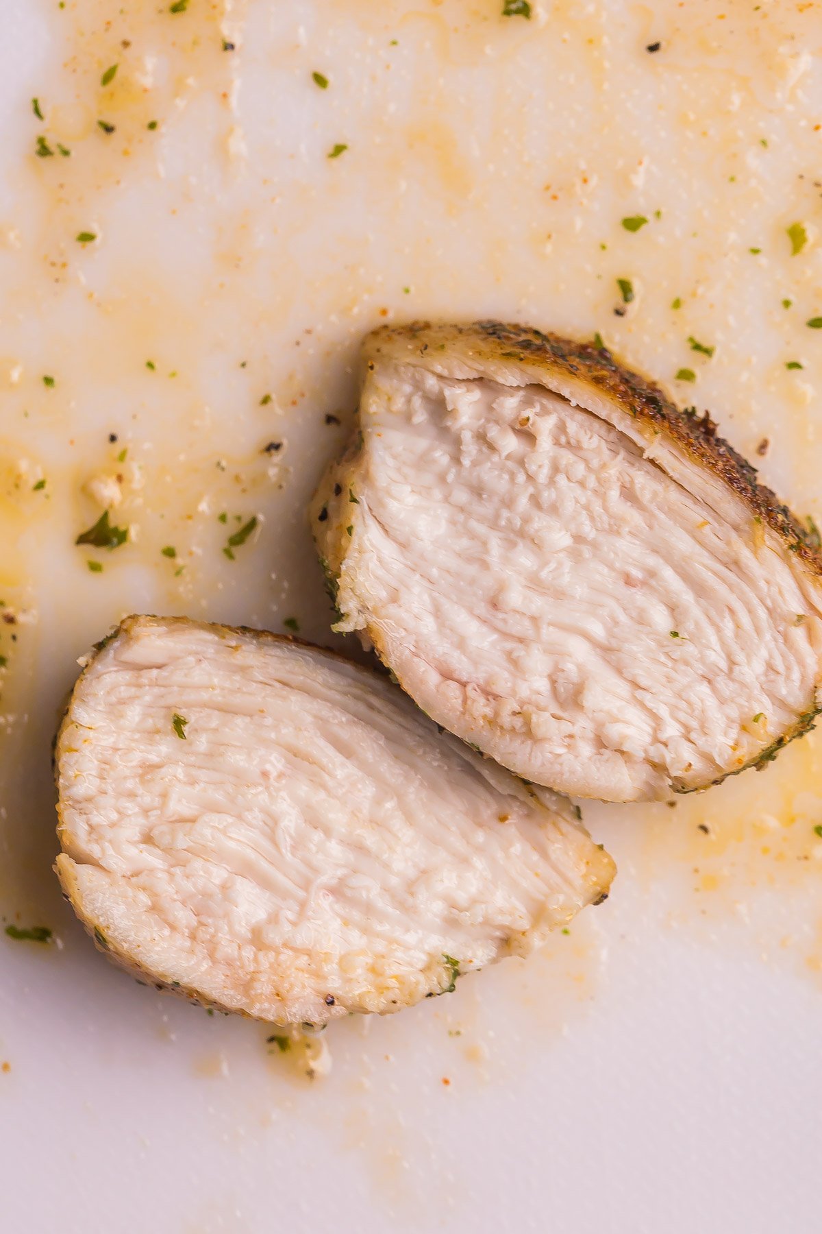 This Air Fryer Chicken Breast is perfectly seasoned and incredibly juicy! It is golden and crispy on the outside and SO flavorful! #chicken #airfryer #recipes #airfryerrecipes two slices of juice air fryer chicken breast on white board.