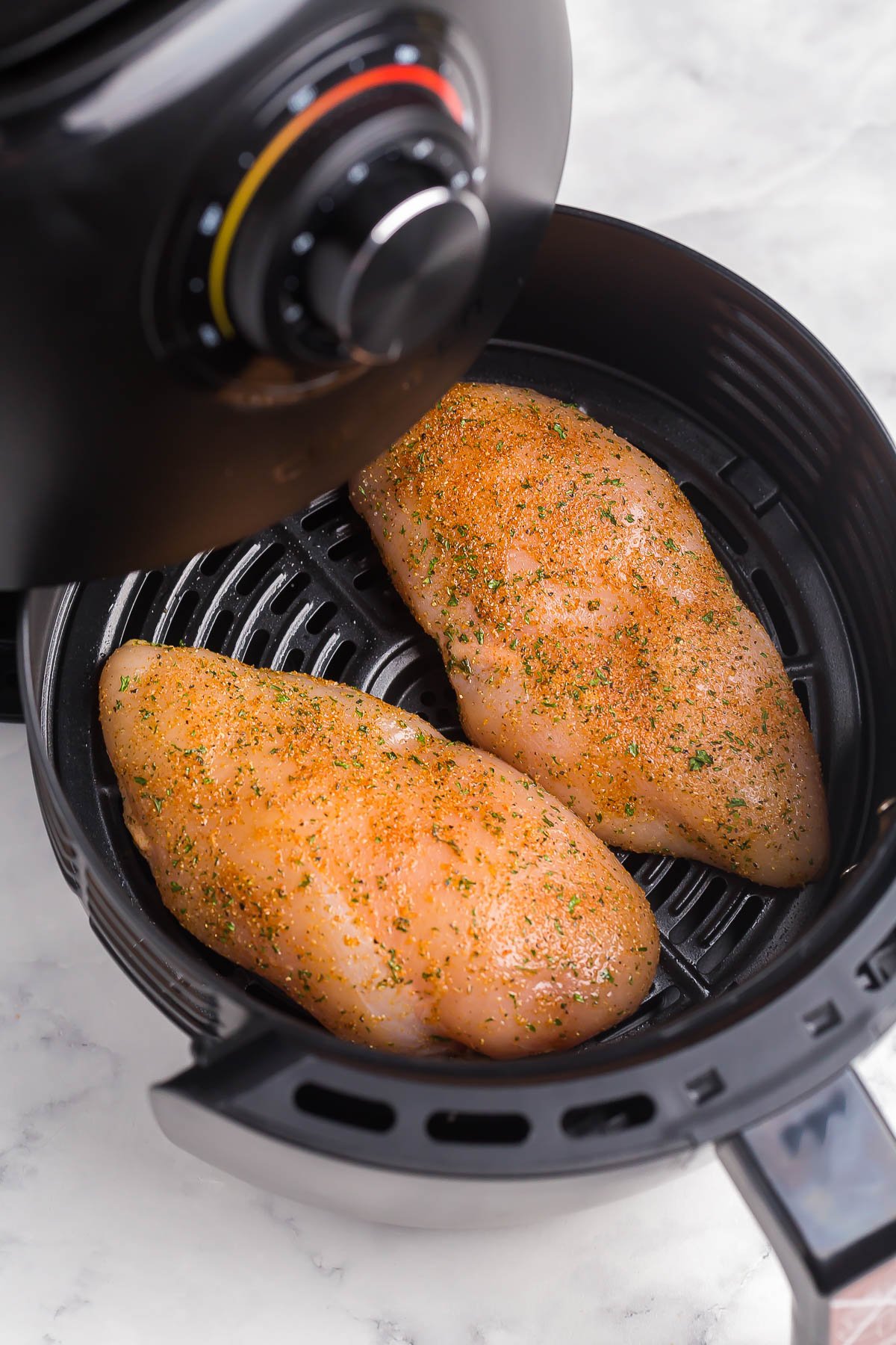 This Air Fryer Chicken Breast is perfectly seasoned and incredibly juicy! It is golden and crispy on the outside and SO flavorful! #chicken #airfryer #recipes #airfryerrecipes uncooked chicken breasts in air fryer.