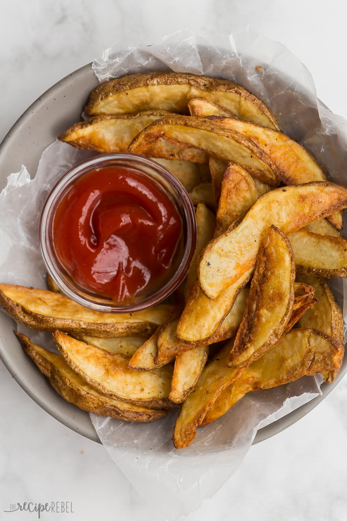 These ultra crispy Air Fryer Potato Wedges are made with just a few simple ingredients and turn out perfectly every time! Golden and crispy on the outside and tender on the inside. #airfryer #recipes #dinner | air fryer recipes | crispy potatoes | homemade fries bowl of crispy potato wedges with small bowl of ketchup