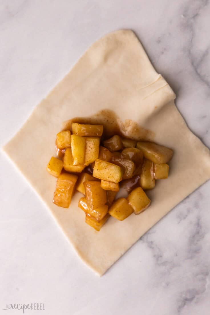square piece of pastry dough with a scoop of apple filling in the centre.
