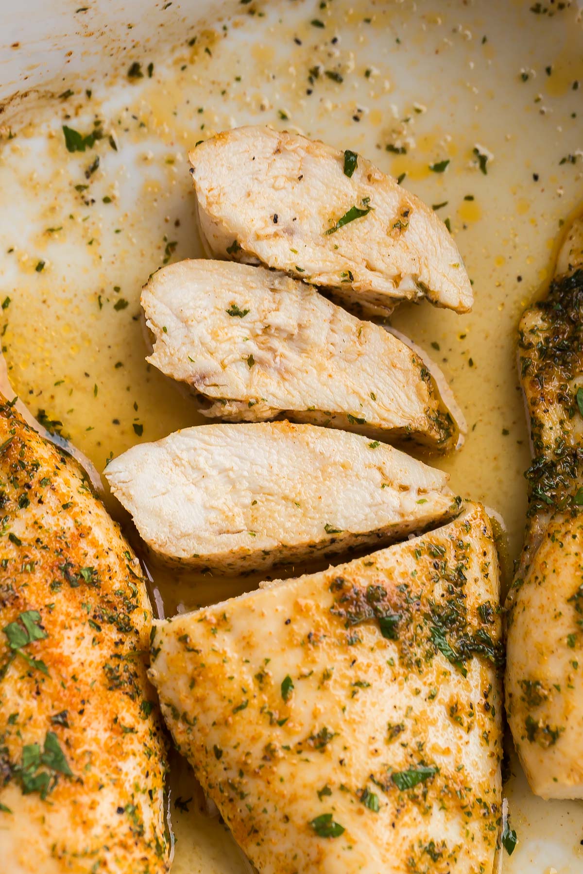 This Baked Chicken Breast comes out juicy and flavorful every time! With a simple spice rub and quick cook time, it's perfect for any night of the week! #chicken #dinner #recipes three slices of baked chicken breasts lying down in pan.