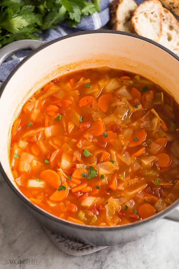 This easy Cabbage Soup is a healthy soup recipe made with just SIX ingredients, including cabbage, carrots, onions, celery, and tomatoes. Dairy free, vegetarian, gluten free and DELICIOUS. #soup #dinner #healthy #healthyrecipes cabbage soup in grey dutch oven with bread in the background
