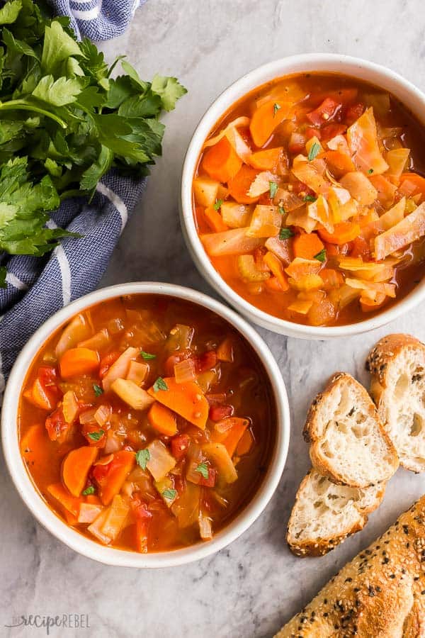 This easy Cabbage Soup is a healthy soup recipe made with just SIX ingredients, including cabbage, carrots, onions, celery, and tomatoes. Dairy free, vegetarian, gluten free and DELICIOUS. #soup #dinner #healthy #healthyrecipes cabbage soup two bowls on grey marble overhead with crusty bread