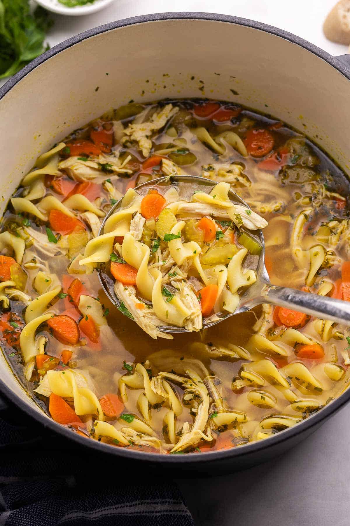This homemade Chicken Noodle Soup is loaded with tender vegetables, shredded chicken, and egg noodles simmered in a delicious broth! It's the perfect hearty, healthy dinner for any night of the week. #soup #dinner #recipe | soup recipes | chicken recipes | chicken breast | chicken soup | comfort food | healthy dinner a scoop of chicken noodle soup coming out of pot.