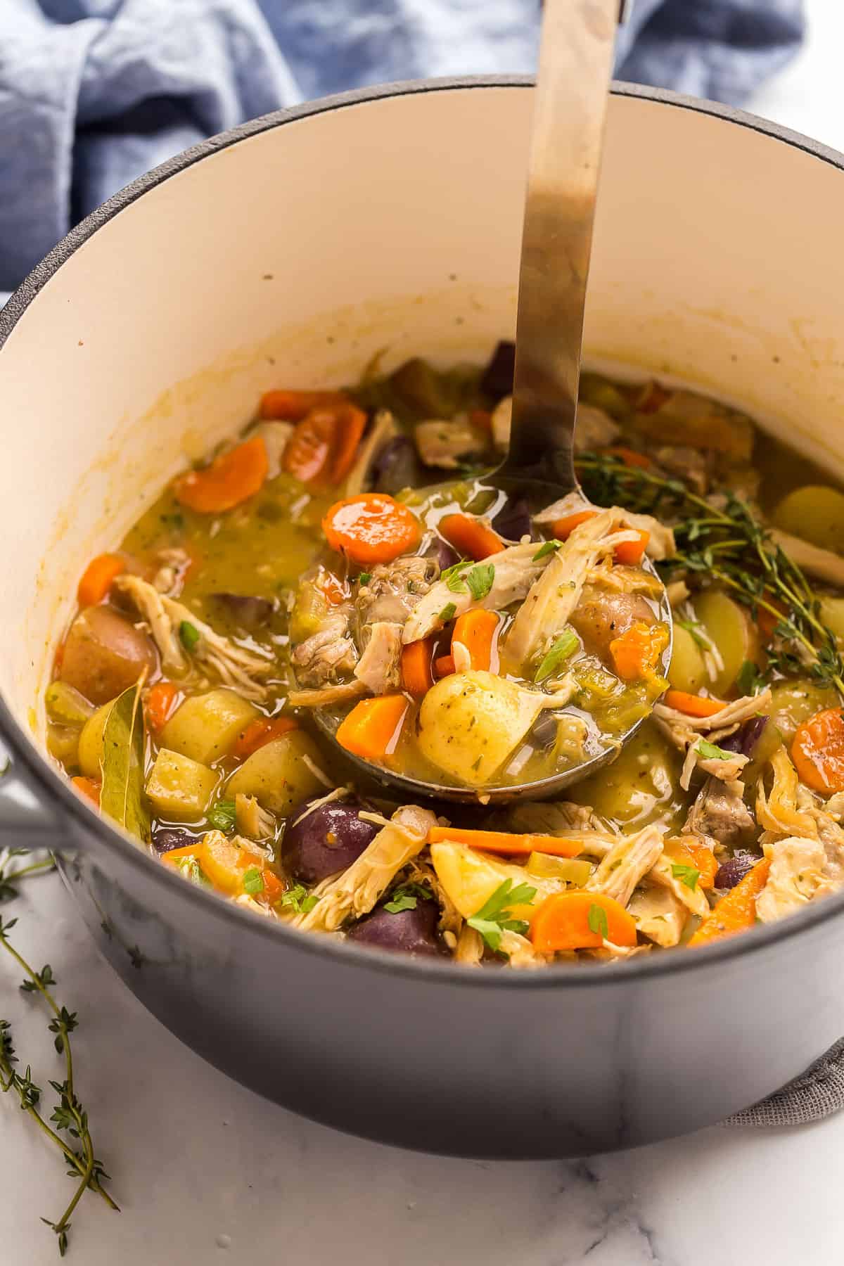 This easy and flavorful Chicken Stew is made in one pot with chicken thighs or breasts, potatoes, carrots, and onions with a rich and creamy sauce. It's easy dinner meets comfort food, perfect any time of year! #soup #recipe #chicken | dinner recipes | dinner ideas | chicken recipes | chicken breast ideas | easy dinner | metal ladle scooping chicken stew from dutch oven.