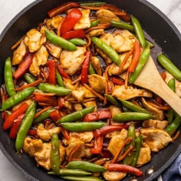 square image of chicken stirfry in black skillet.