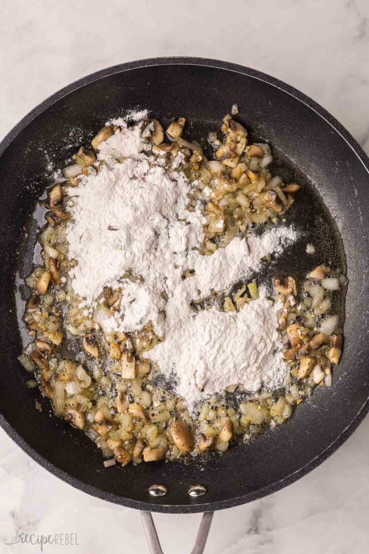 flour added to other ingredients in black pan.