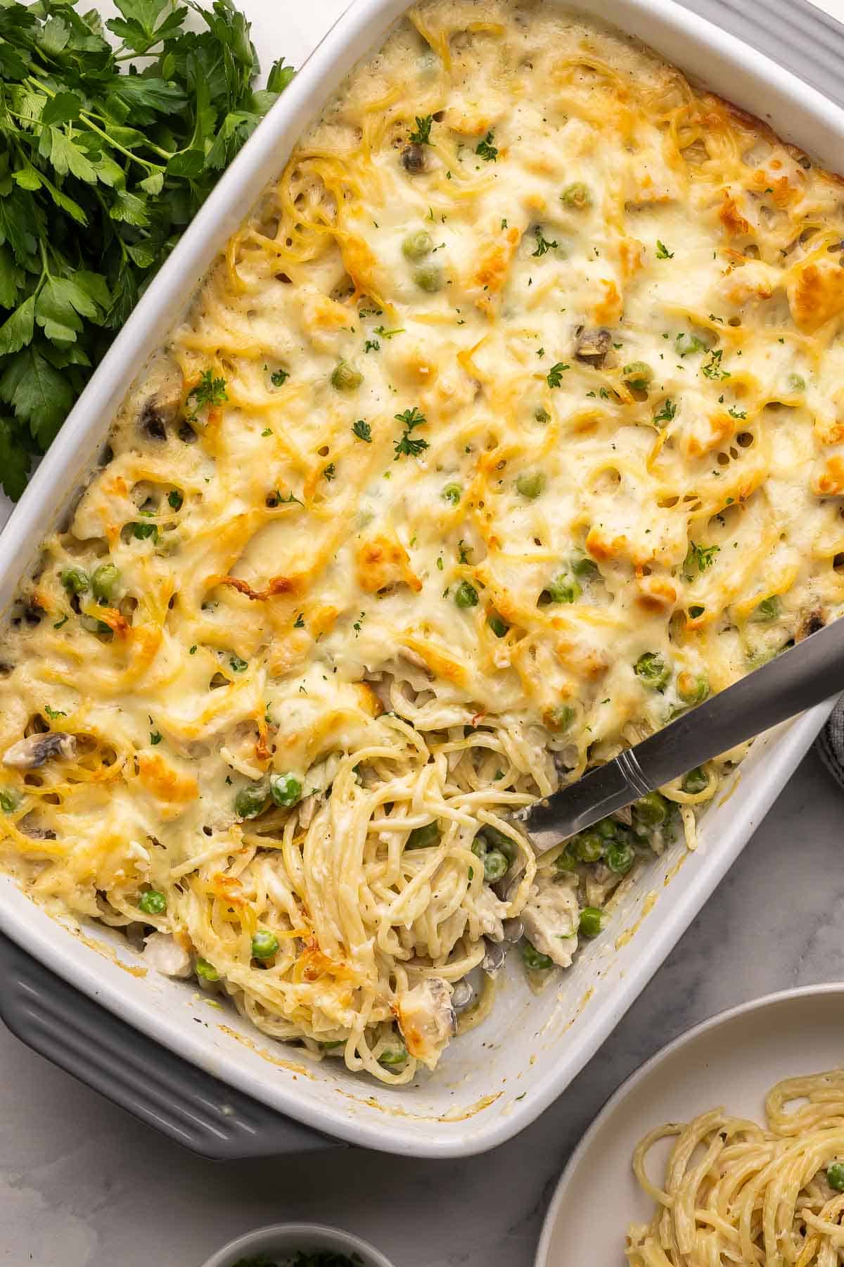 overhead image of chicken tetrazzini in a baking dish with scoop stuck in.