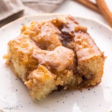 close up of a piece of cinnamon roll cake on a white plate.