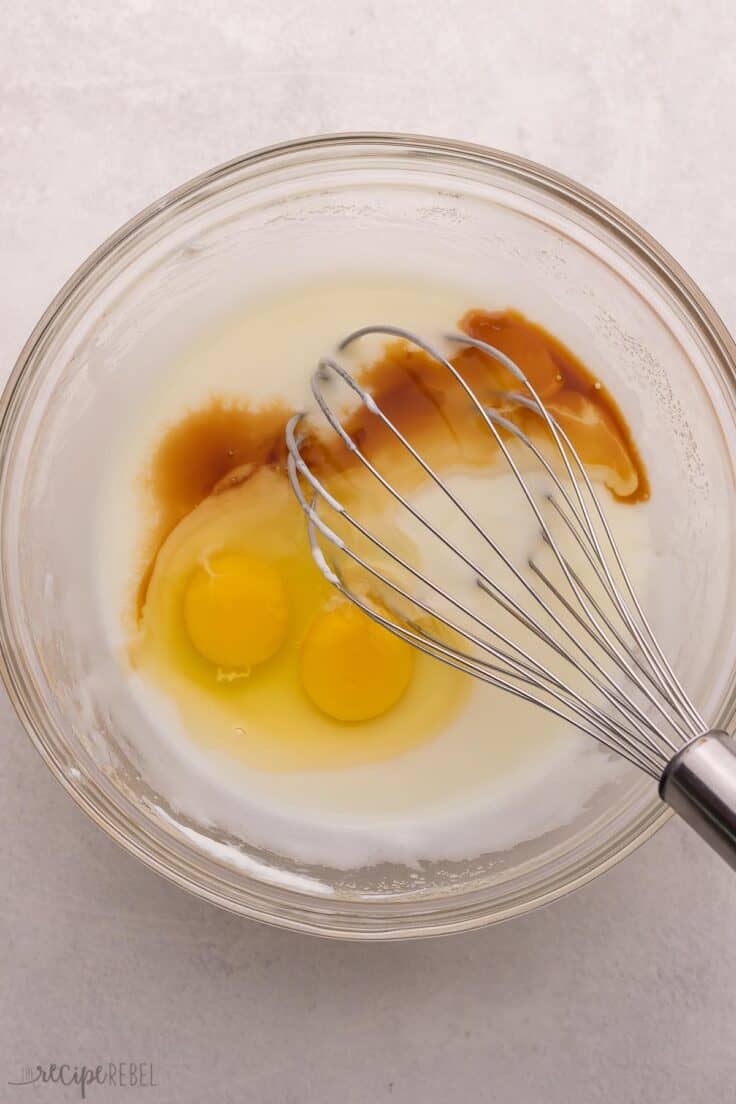 eggs and other unmixed ingredients in glass bowl with whisk.