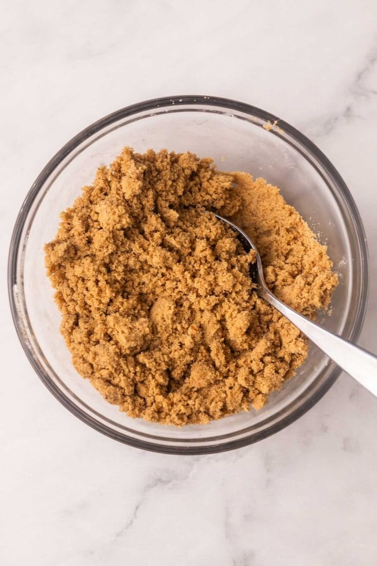 glass mixing bowl with mixed ingredients and a spoon in it.