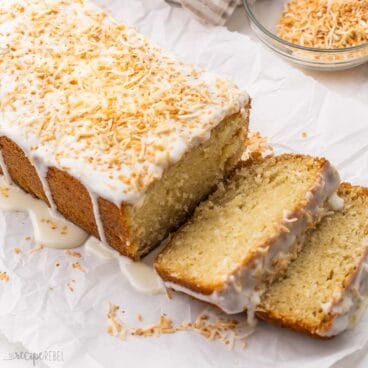 a loaf of sliced coconut bread with glaze topped with toasted coconut.