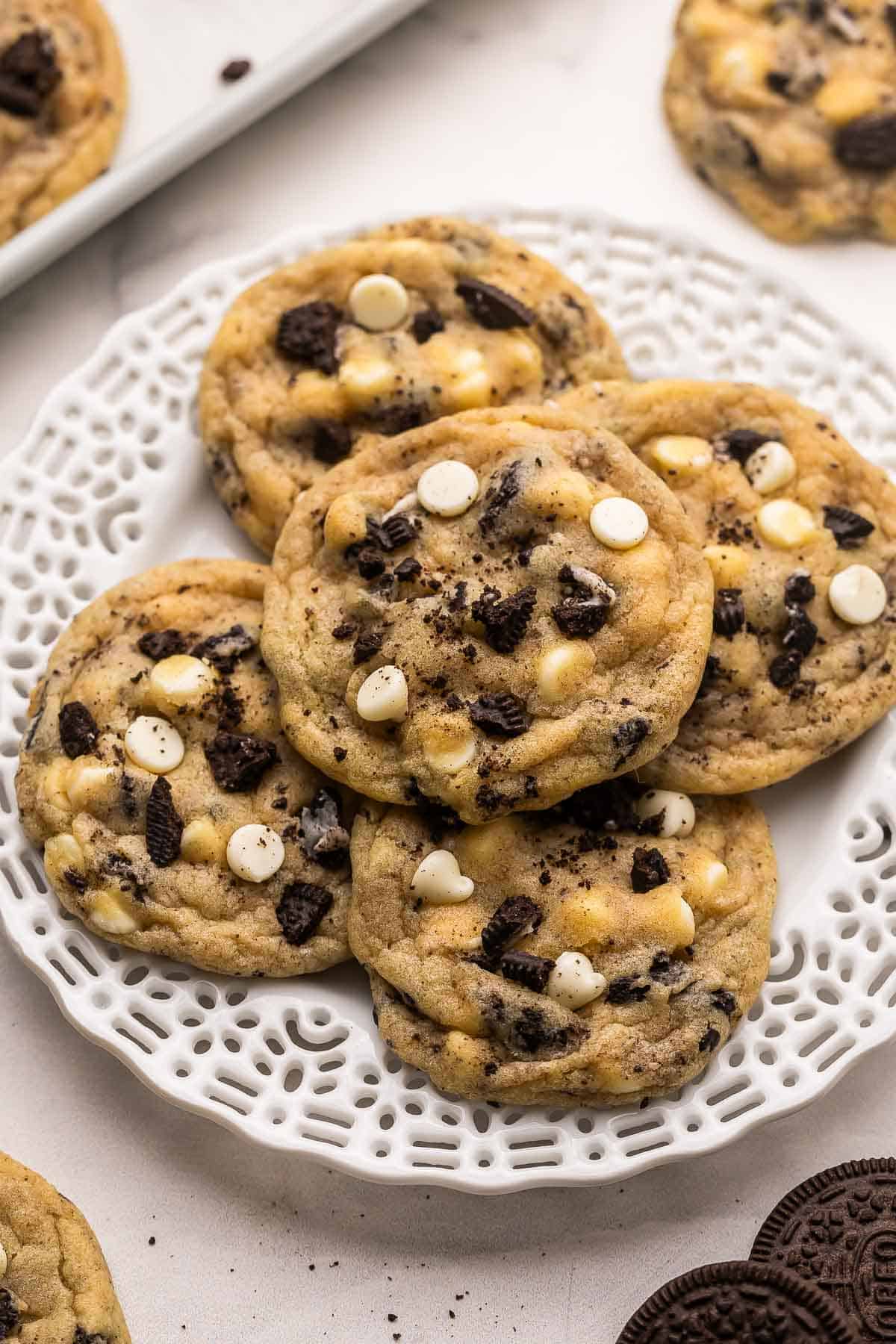 These Cookies and Cream Cookies are everything you love about the classic combo in chewy cookie form! They're made with Oreo cookie chunks, white chocolate chips, and a basic cookie base for a fun twist on the iconic duo. | cookie recipe | oreo cookies | oreo desserts | baking from scratch | homemade cookies cookies and cream cookies on a white plate.