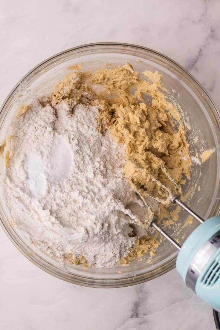 flour added to other ingredients in glass mixing bowl.