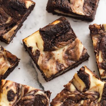 several pieces of cream cheese brownies on a white background