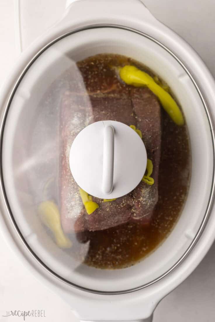 italian beef cooking in slow cooker with lid on.