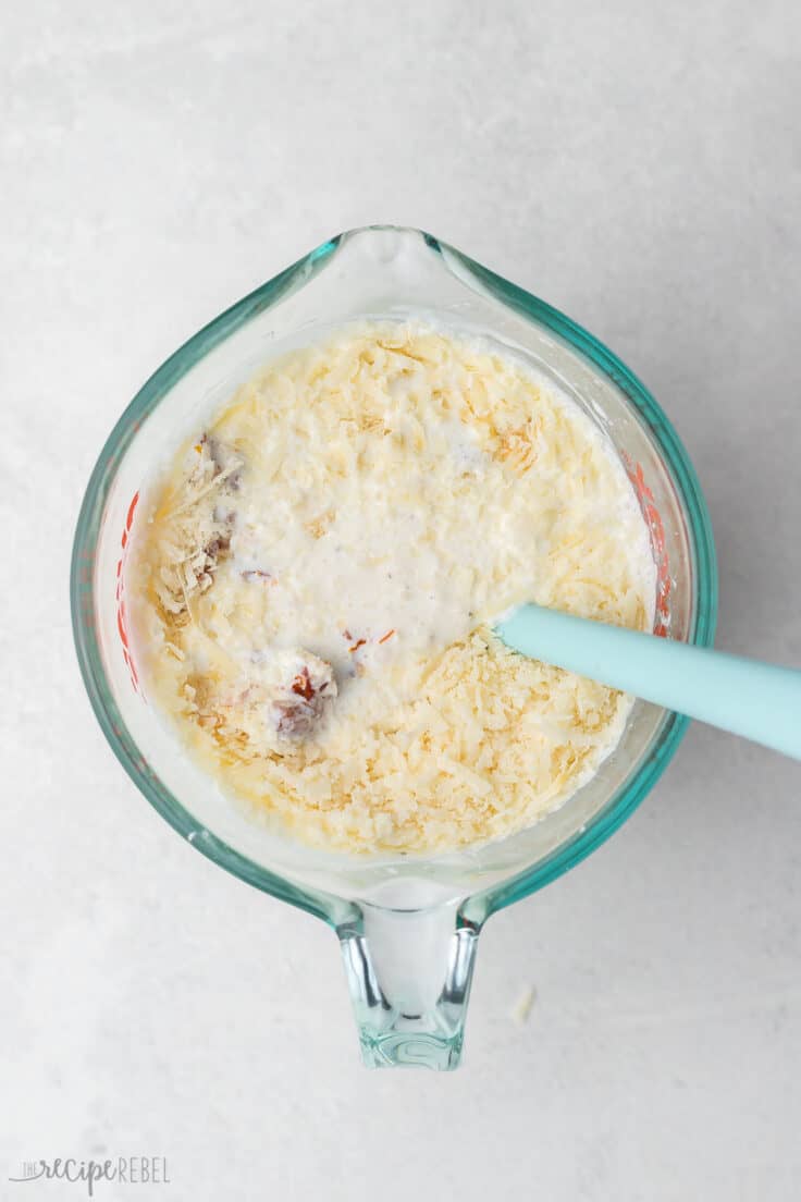 tuscan cream sauce in a glass measuring cup with spatula.