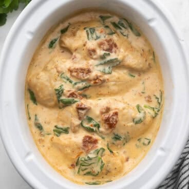 square image of crockpot chicken breast with tuscan cream sauce in slow cooker.