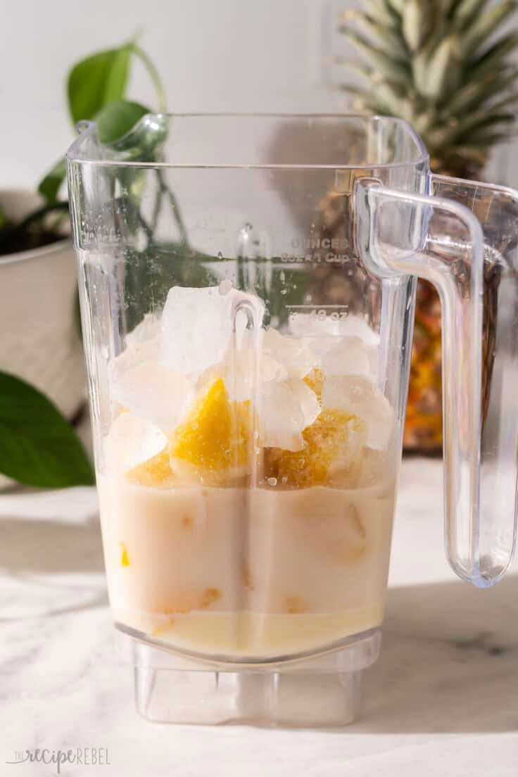 a blender filled with ingredients needed for pina colada slushy.