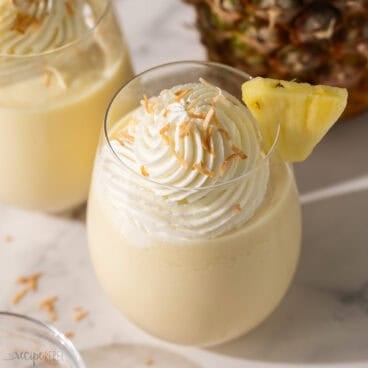 a glass of pina colada slushy topped with toasted coconut.