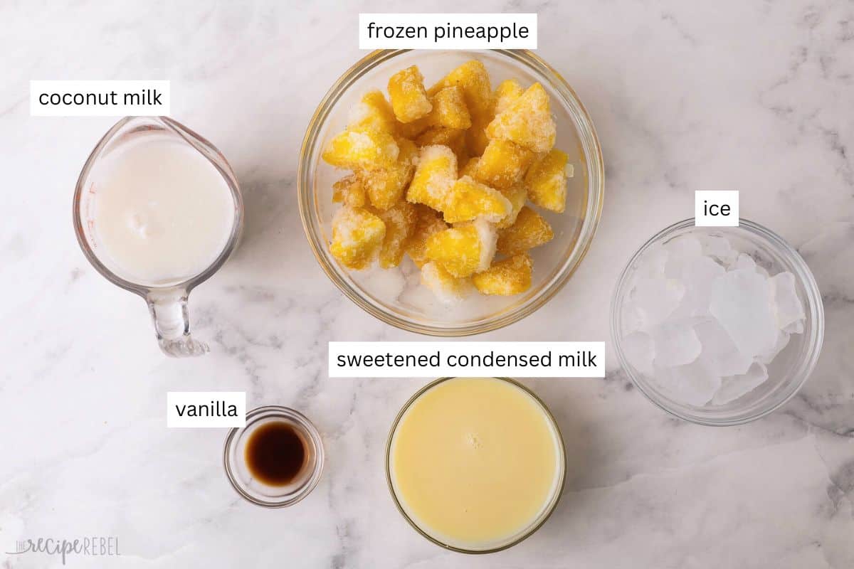 Get a taste of the tropics with this Frozen Pina Colada slushy recipe! It's made with creamy coconut milk, condensed milk, vanilla, frozen pineapple, and tons of ice for a drink that feels like a beach vacation. #drink #recipe #mocktail | mocktail recipe | drink recipe | summer drink | frozen drinks | blended drink recipe ingredients needed for pina colada slushy in bowls.