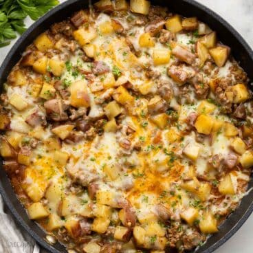 large pan of ground beef and potatoes topped with chopped parsley.