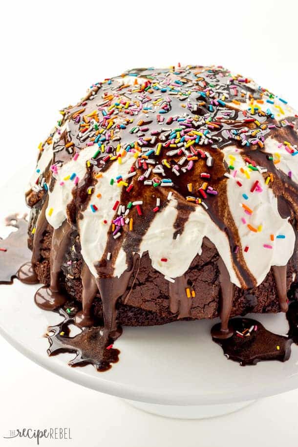 Ice Cream Brownie Mountain: A fun new ice cream cake! Rich, fudgy brownies filled with homemade ice cream (or use store bough and keep it simple!) and topped with chocolate ganache, whipped cream, chocolate sauce and sprinkles -- the perfect cake for a birthday or celebration! Change up the ice cream flavors to suit your tastes! www.thereciperebel.com ice cream brownie mountain up close with whipped cream chocolate sauce and sprinkles
