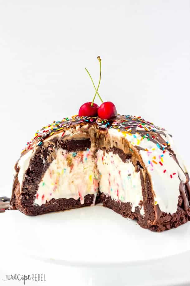 Ice Cream Brownie Mountain: A fun new ice cream cake! Rich, fudgy brownies filled with homemade ice cream (or use store bough and keep it simple!) and topped with chocolate ganache, whipped cream, chocolate sauce and sprinkles -- the perfect cake for a birthday or celebration! Change up the ice cream flavors to suit your tastes! www.thereciperebel.com inside view of brownie mountain ice cream cake with brownies on the bottom and sides and ice cream in the middle