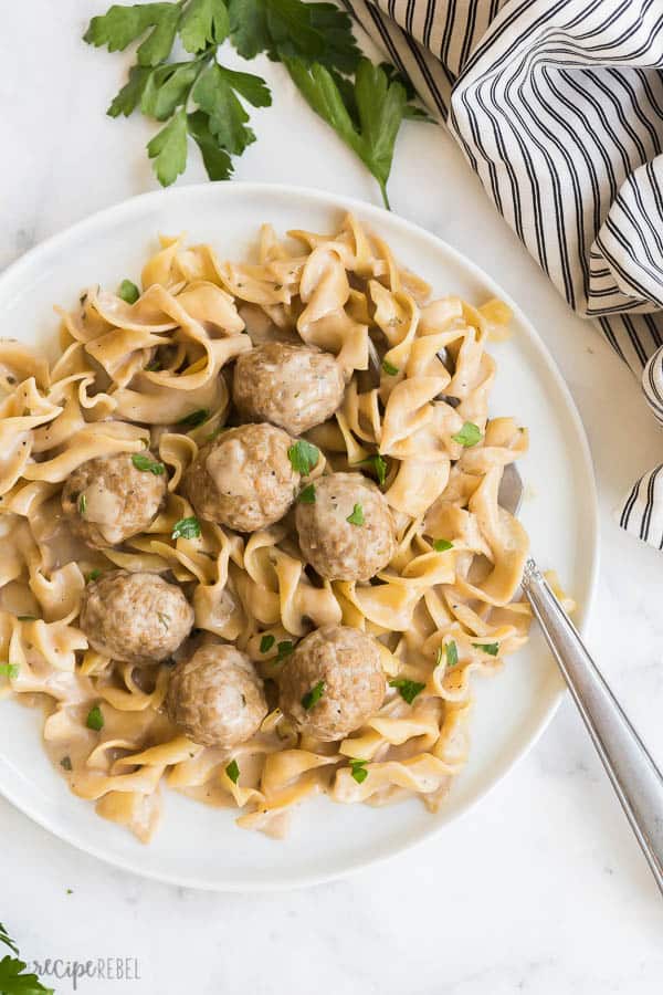 These Instant Pot Swedish Meatballs and Noodles are an easy one pot meal made in the pressure cooker! Made in 30 minutes or less. #instantpot #pressurecooker #meatballs #recipe #recipes instant pot meatballs on white plate on white background with fork stuck in noodles