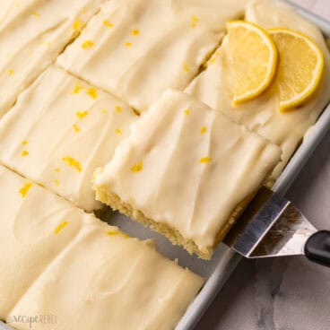 a piece of lemon sheet cake being lifted out of pan.