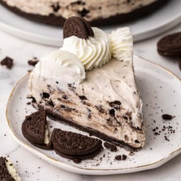a plate with apiece of no bake oreo cheesecake and oreos beside.