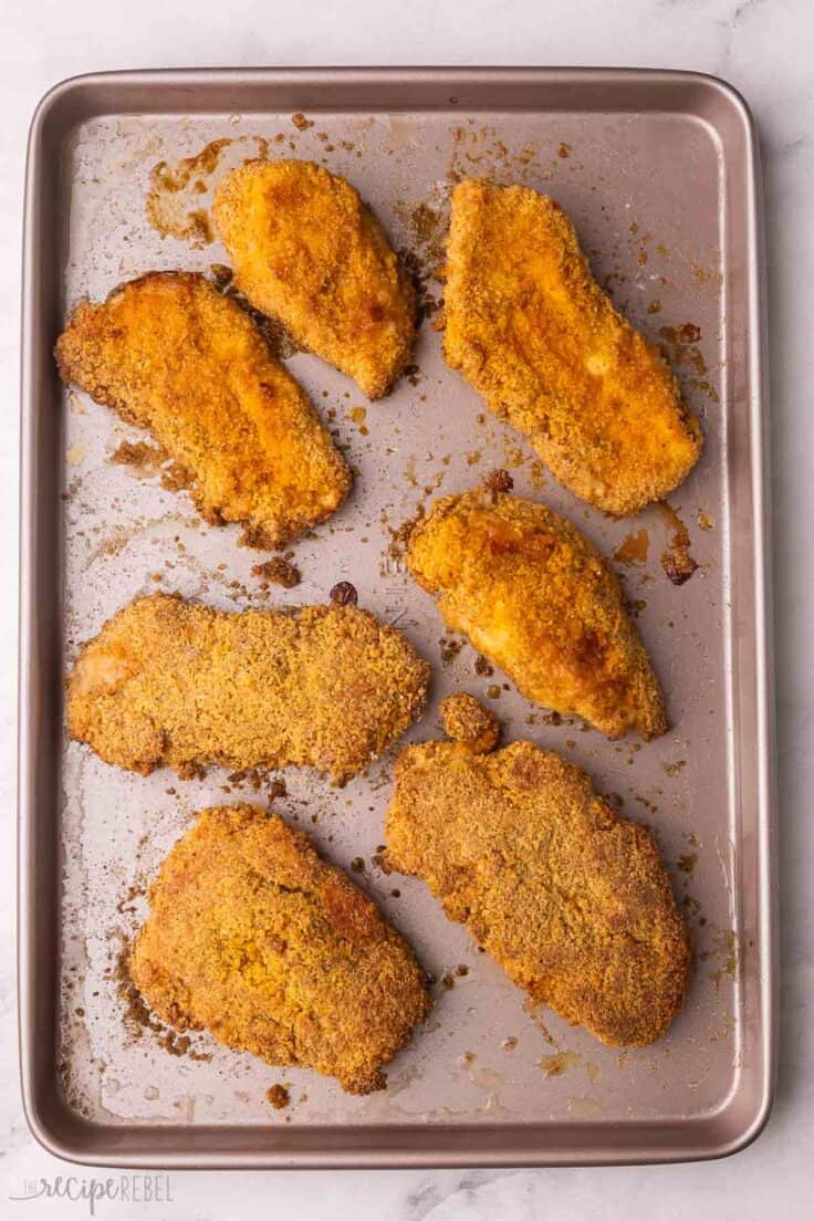 large baking sheet full of oven fried chicken.