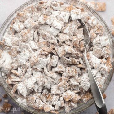 big glass bowl of puppy chow with steel spoon in it.