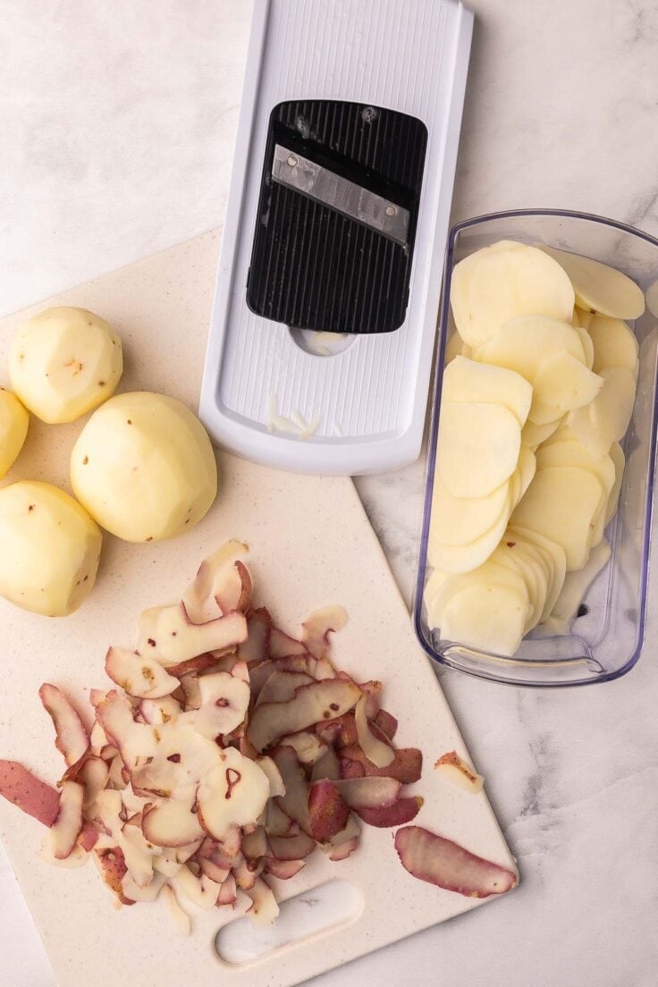 sliced and peeled potatoes on a cutting board.