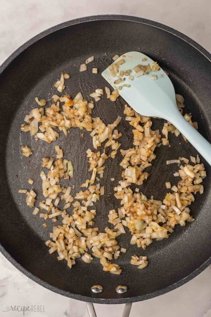 sauteed onions and spatula in black frying pan.