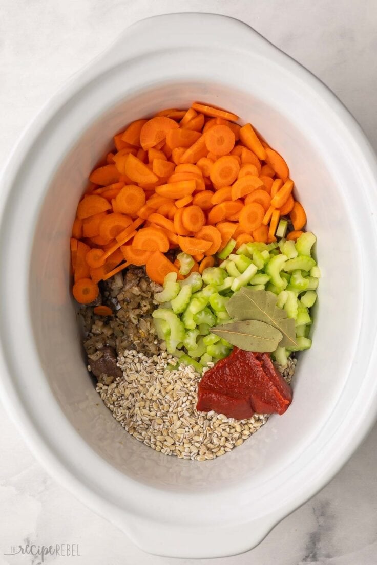 chopped vegetables added to white slow cooker.