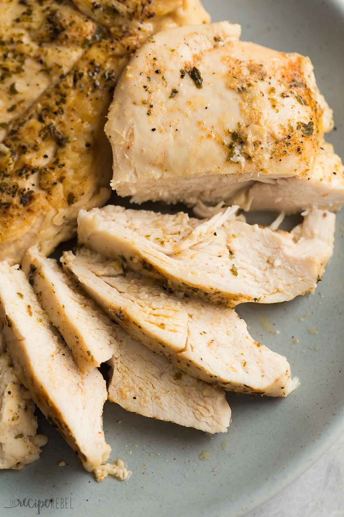 This Slow Cooker Chicken Breast recipe comes out perfectly juicy and seasoned every time! Learn my tips for getting the best crockpot chicken breast, perfect for salads, sandwiches or an easy dinner. #slowcooker #crockpot #chicken #chickenbreast #recipe #healthy sliced crockpot chicken breast on grey plate.