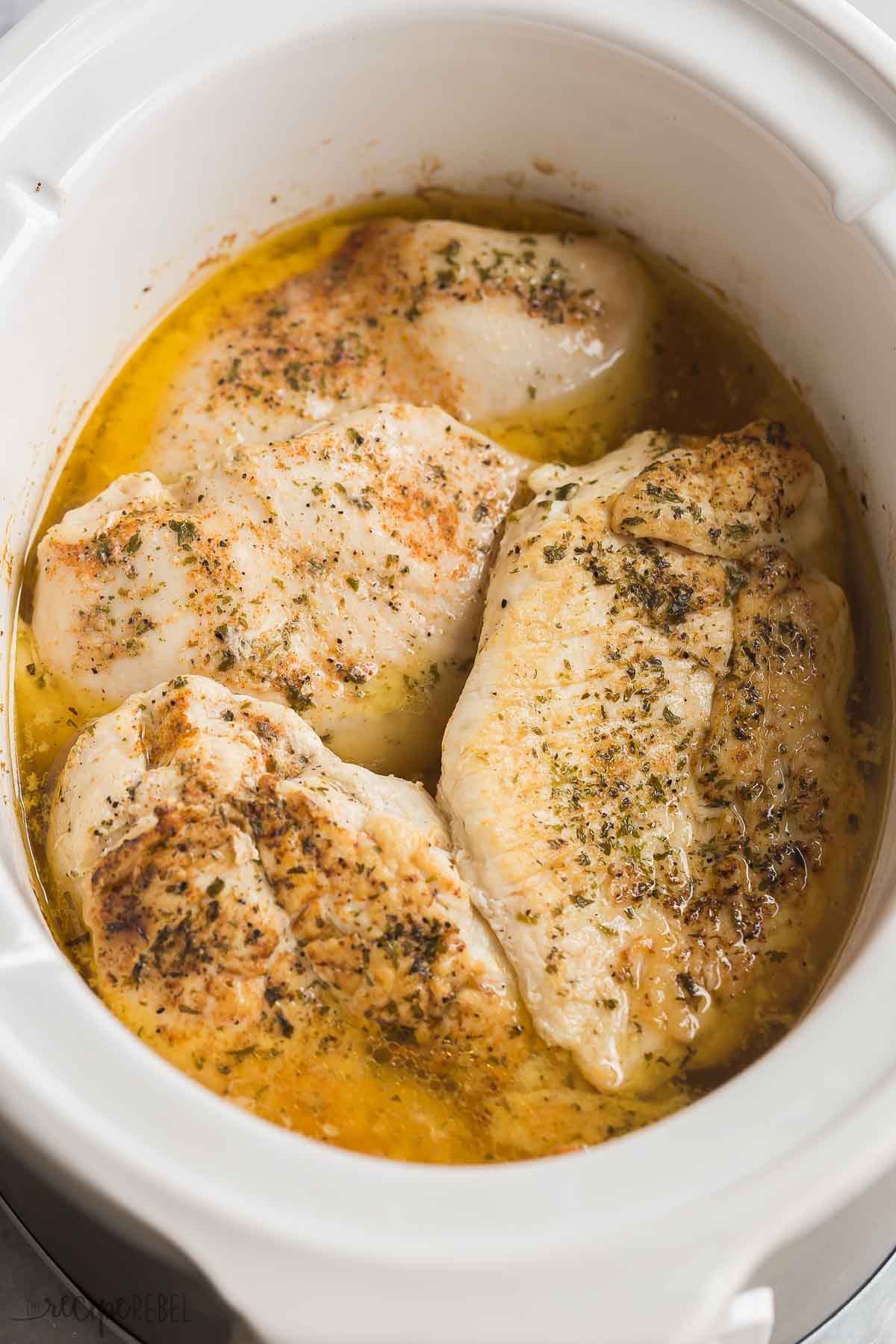 This Slow Cooker Chicken Breast recipe comes out perfectly juicy and seasoned every time! Learn my tips for getting the best crockpot chicken breast, perfect for salads, sandwiches or an easy dinner. #slowcooker #crockpot #chicken #chickenbreast #recipe #healthy crockpot chicken breast in white slow cooker with juices.