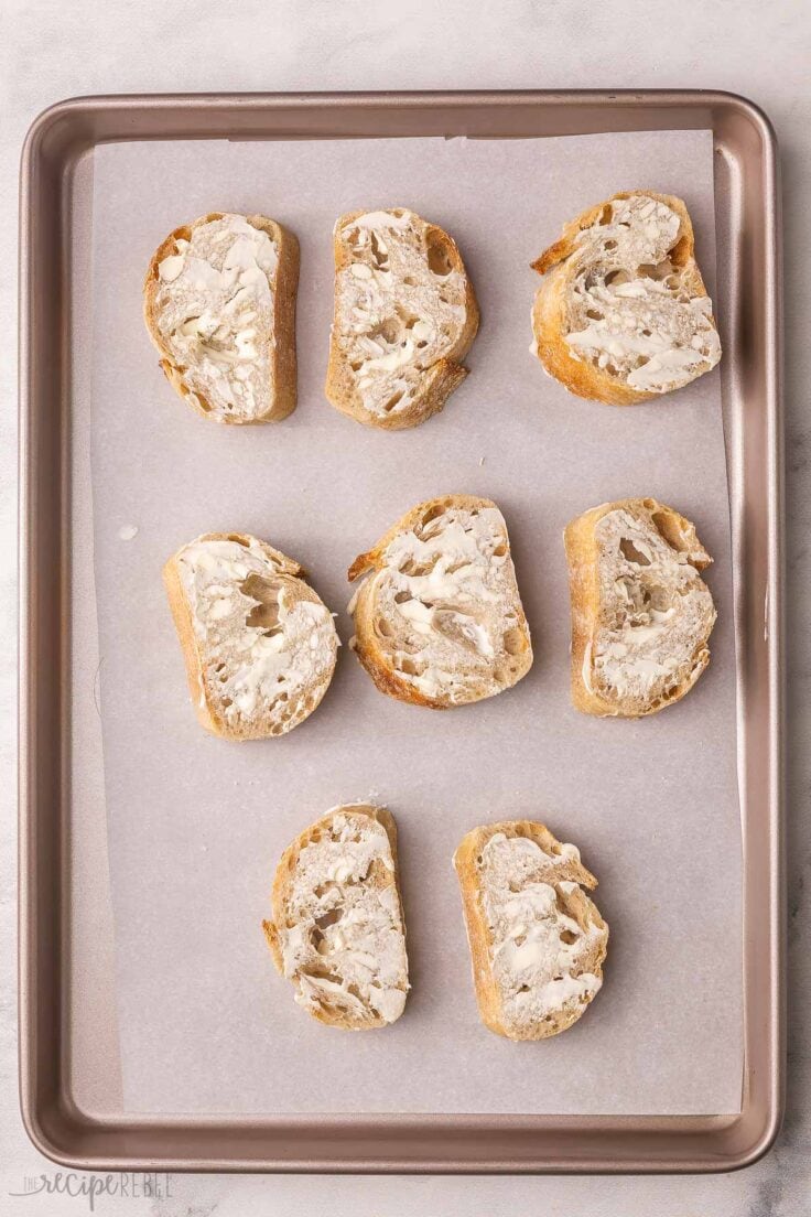 grey baking sheet with buttered french bread.