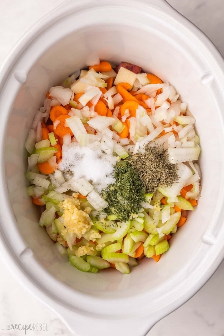 large white slow cooker filled with chopped vegetables and spices.