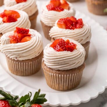 strawberry cupcakes topped with chopped strawberries on a white plate.
