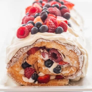 square image of angel food roll cake with fresh berries.