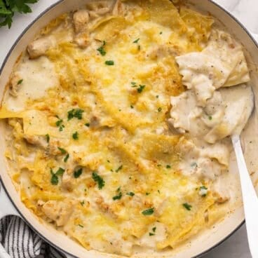 large scoop in pan of white chicken skillet lasagna.